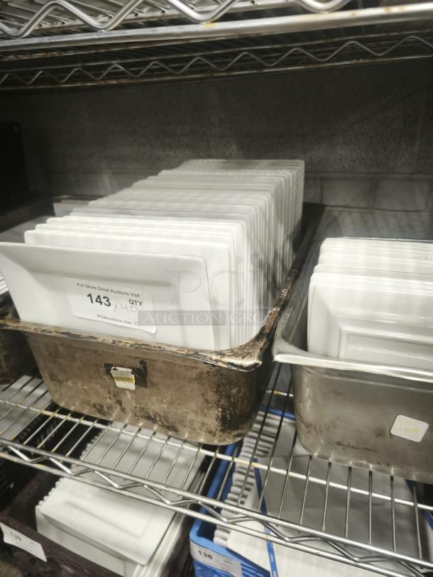 9" bright white square porcelain plates stacked in metal tray, labeled with "143 QTY" for auction. Clean and pristine condition.