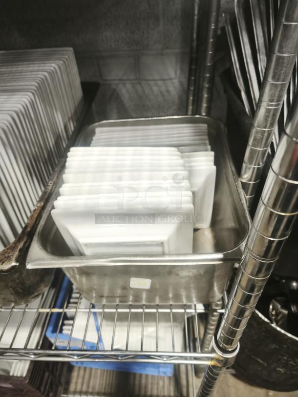Stack of rectangular bright white square porcelain plates in metal tray, excellent condition, no visible markings.