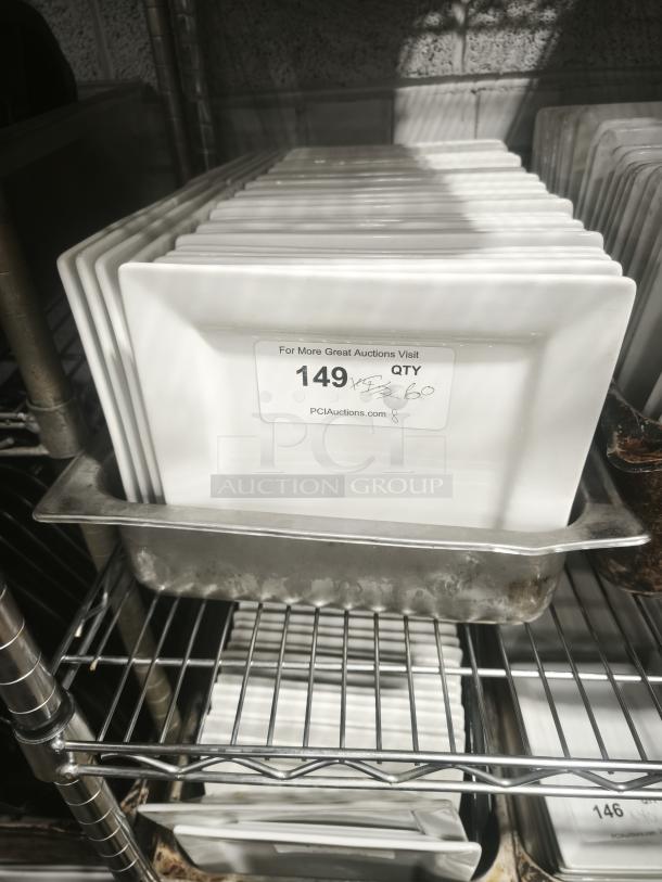 Set of 9 bright white square porcelain plates on a metal rack. One plate shows label with quantity and auction site URL.