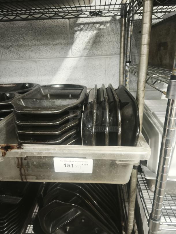 Iron griddle pans stacked on metal shelves, showing wear. Label indicates auction item quantity as 151.