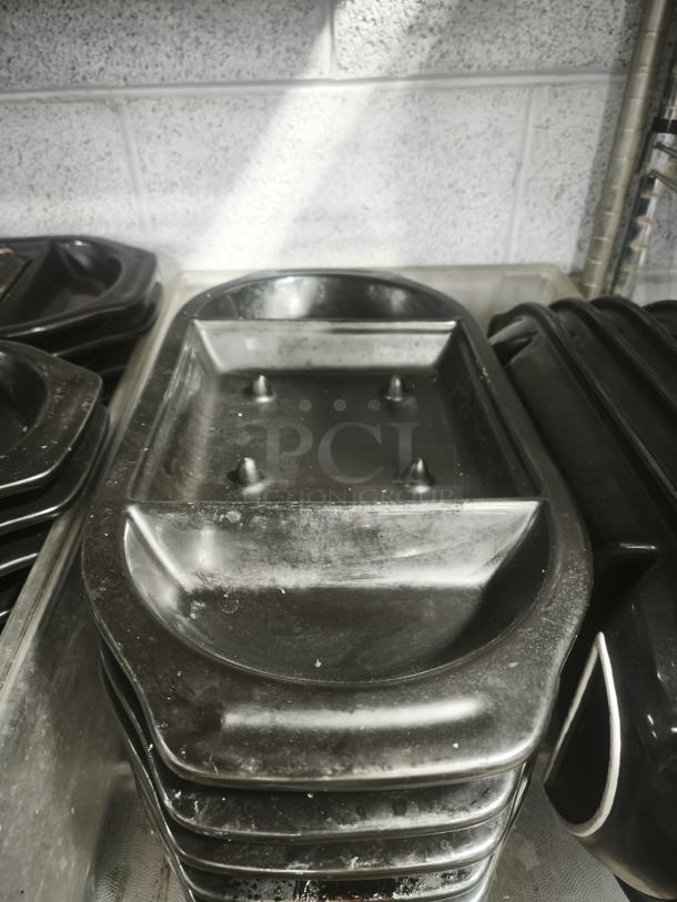 Iron griddle pan with raised ridges, in used condition, stacked among similar pans; no visible brand or markings.