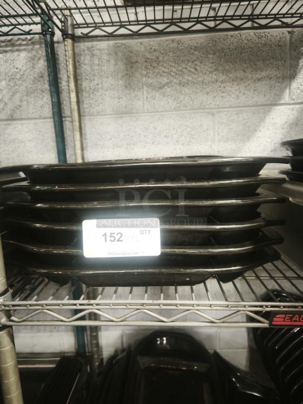 Stack of iron griddle pans on metal shelf. Tag indicates quantity: 152. Suitable for cooking; durable and multipurpose.