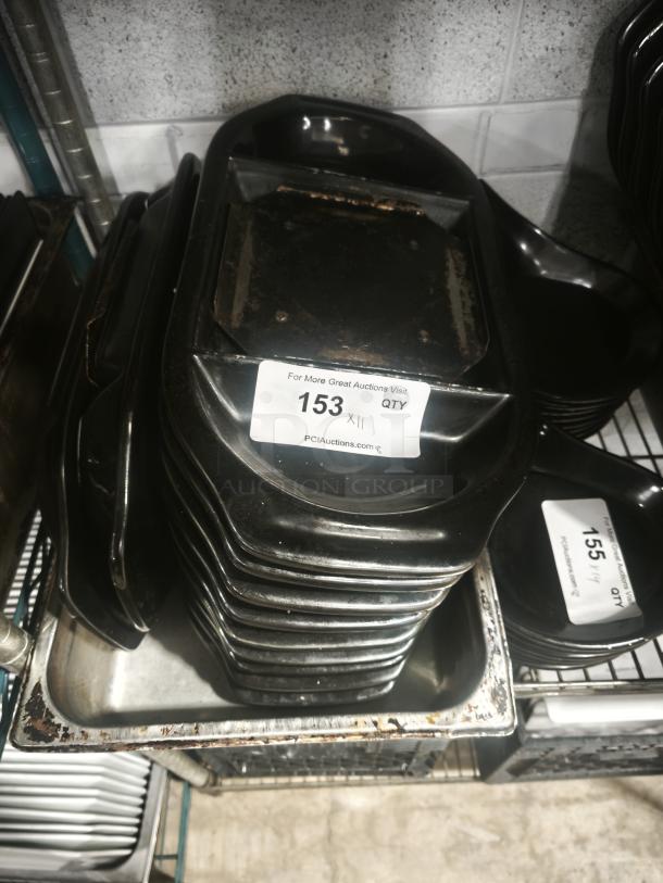 Stack of used iron griddle pans with prominent wear marks, auction label "153 QTY" visible, black handles.