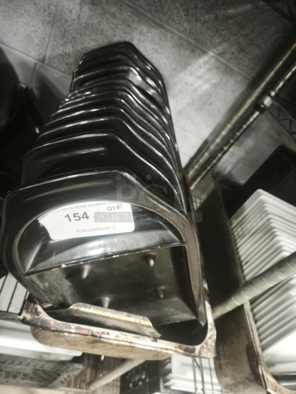 Stack of iron griddle pans, black, used condition, visible auction tag "154 x 13 QTY" indicating quantity, on shelf.