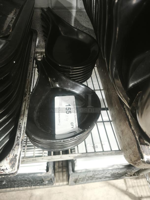 Black ceramic serving dish set, glossy finish, stacked on a metal shelf. Visible tag indicates quantity: 14.