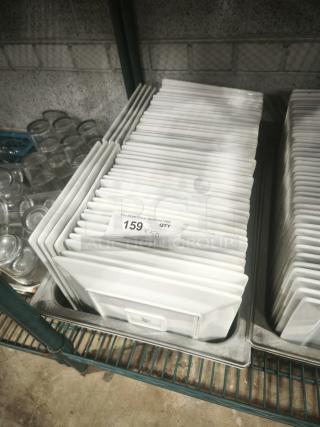 Stack of 9" bright white square porcelain plates in new condition, showing auction label "159 x 50."
