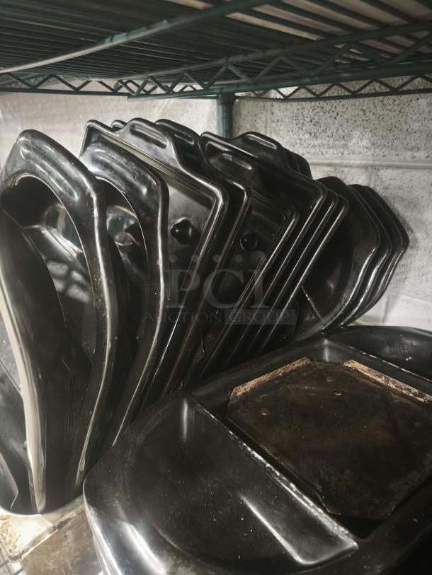 Stack of black iron griddle pans on shelf; durable construction; some show use with surface discoloration.