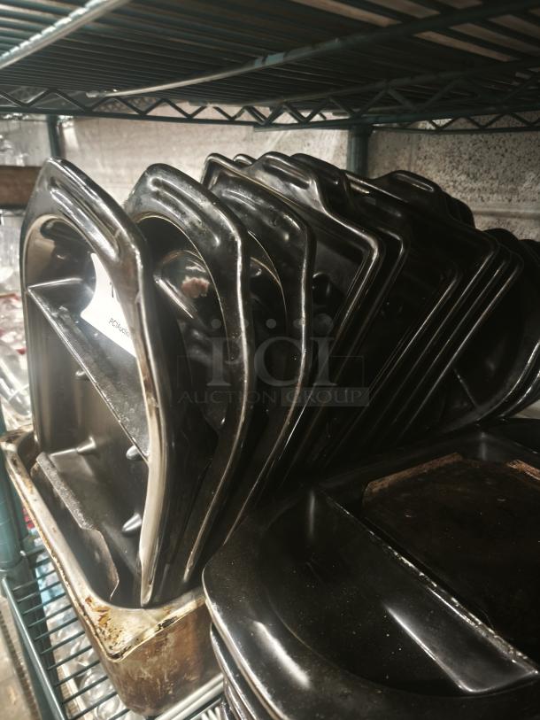 Stack of iron griddle pans on a metal shelf, showing signs of wear and rust; no visible brand markings.