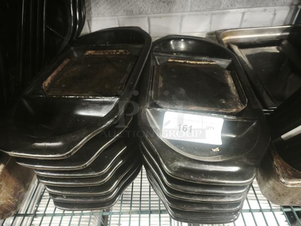 Stacked iron griddle pans with visible wear, featuring a flat rectangular cooking surface. Auction label reads "161 QTY."