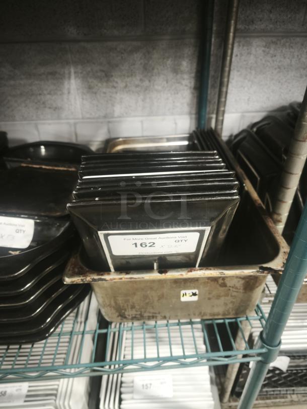 Stack of 6"x8" rectangular black porcelain plates, used condition, with auction label indicating quantity of 162.