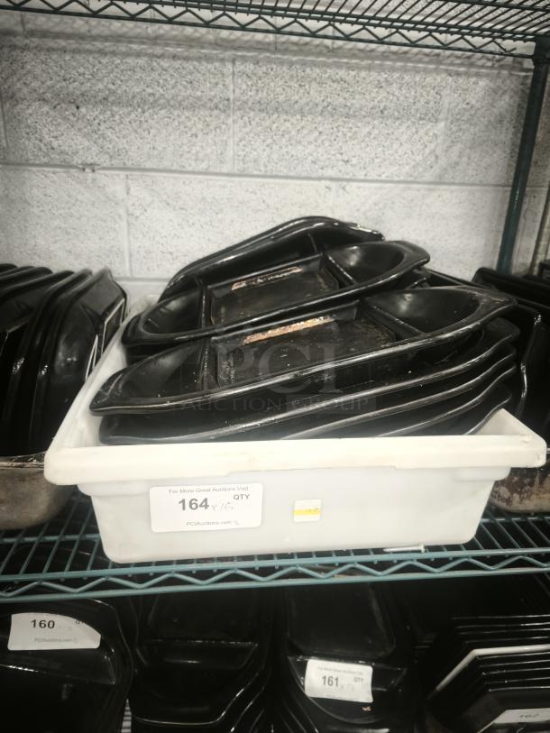 Black Rock Bar and Grill hot stone serving platters in black, stacked in a storage container. Each shows signs of use.