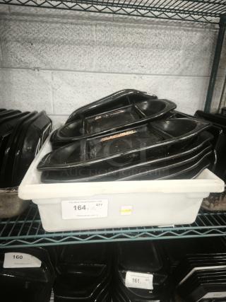 Black Rock Bar and Grill hot stone serving platters in black, stacked in a storage container. Each shows signs of use.