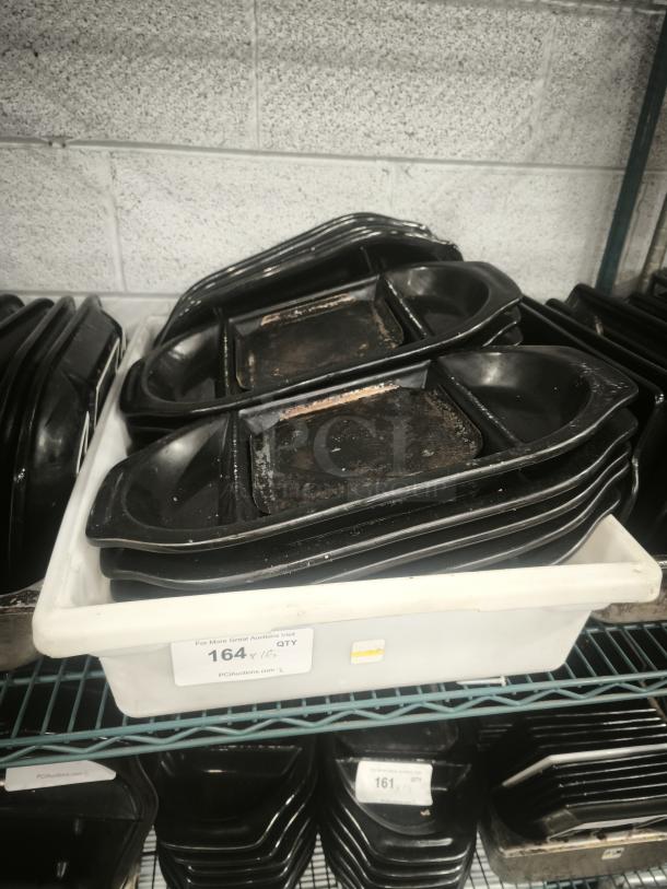 Black stone serving platters stacked on a shelf, used condition, labeled "164" for auction quantity.