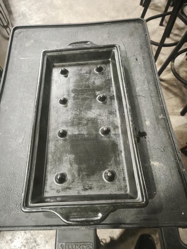 Black stone serving platter with textured surface and integrated handles, used for bar and grill service; shows signs of use.