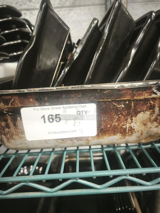 Black rock serving platters stacked on shelf, used for hot stone grilling; tag reads "165 Qty" indicating auction lot number.