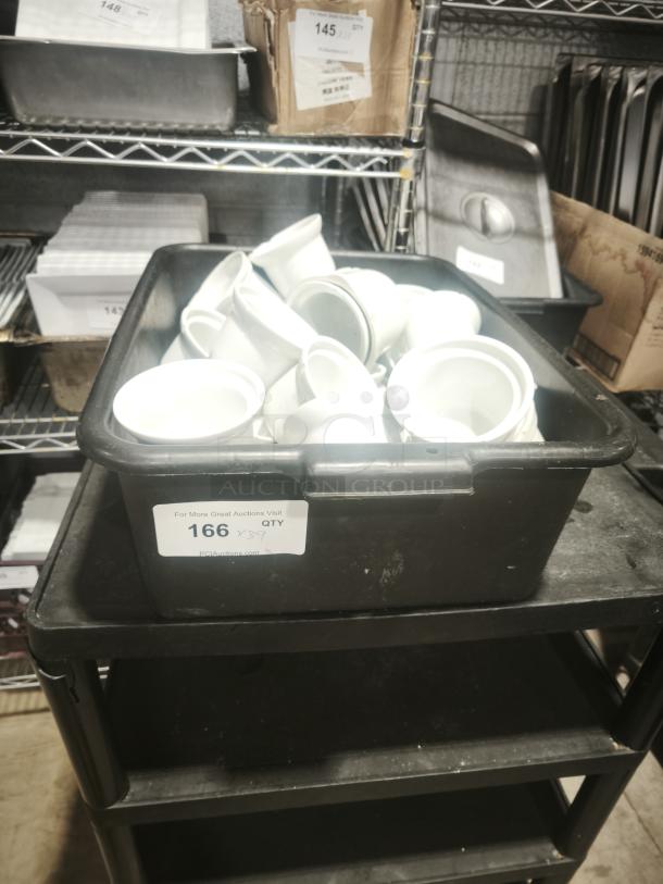 A stack of Aluma White Medium Porcelain Pot Pie Dishes in a black bin, placed on a shelving unit. Labels indicate quantity.