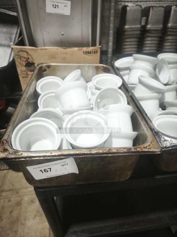 A batch of Aluma White Medium Porcelain Pot Pie Dishes, shown in a metal container. Clean, pristine condition. Auction tag indicates quantity of 26.