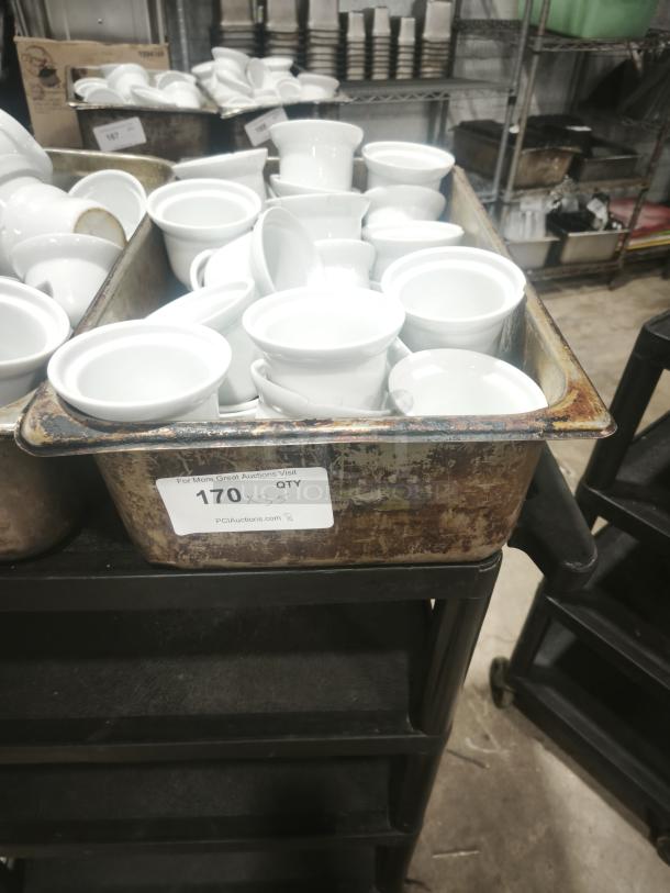 White porcelain pot pie dishes in bulk, medium size, Aluma brand, shown in a rustic bin, includes auction label indicating 170 units.