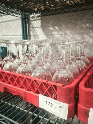 Set of wine glasses in red crate, visibly clean, in good condition. Label shows auction number 173, quantity 31.