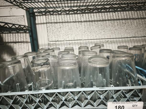 Vintage glass tumblers in good condition, placed upside down on a blue rack, ideal for restaurants or collectors.