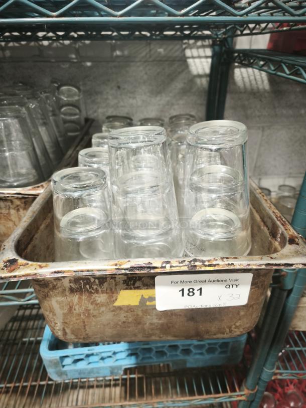 Vintage restaurant glass tumblers, clear, used condition, set of 32 in a metal bin. Auction lot number 181 visible.