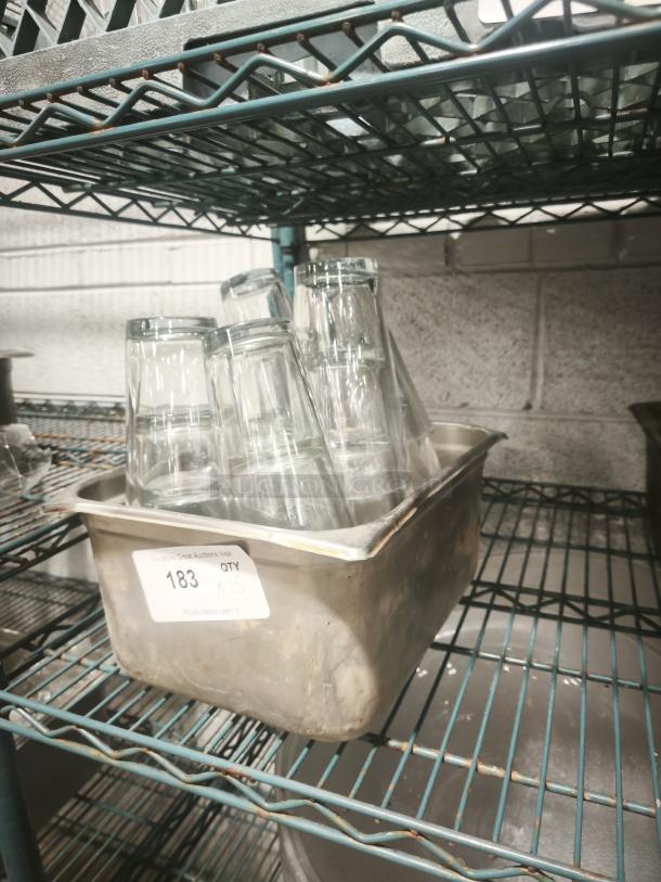 Vintage glass tumblers in metal pan, set of 15, clear glass, stored on wire rack. Auction tag indicates quantity and lot number.
