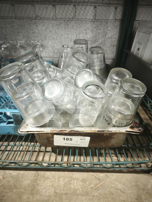 Vintage glass tumblers in a metal tray, quantity 37, used, restaurant-style, clear glass with cylindrical shape.