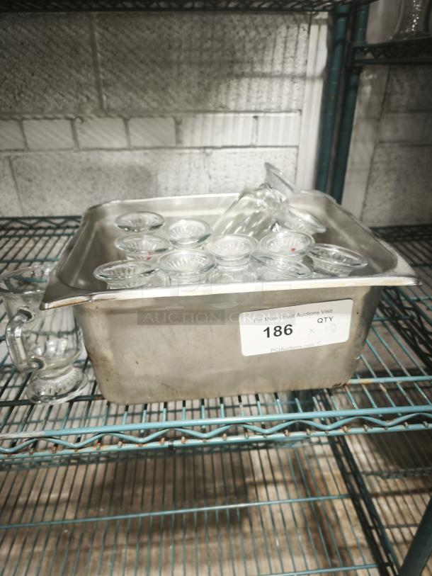 Clear glass footed items, 6" tall, in metal container on shelf. Quantity label indicates 12 pieces. Clean, good condition.