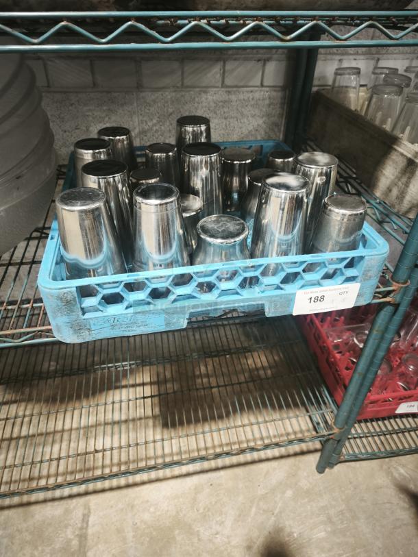 Vintage stainless steel cocktail shakers in a blue crate, reflective finish, good condition, stacked on a metal shelf.