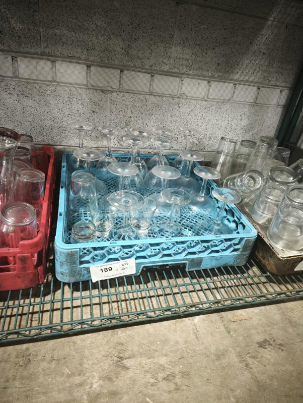 Wine glasses on a blue crate in a storage area, quantity label visible. Various glass shapes, seemingly used condition.