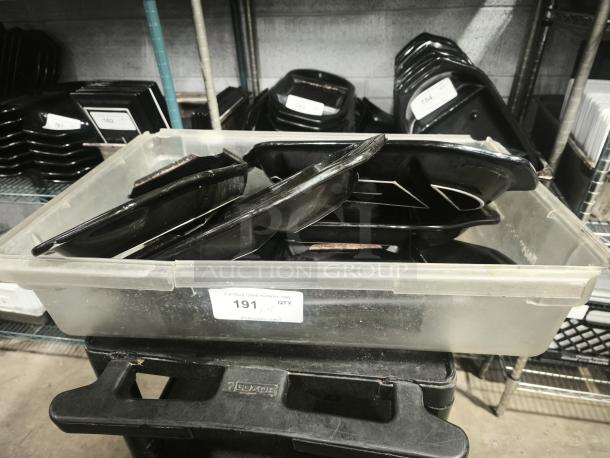 Black rock bar and grill hot stone serving platters, stacked in a clear plastic bin, in used condition.