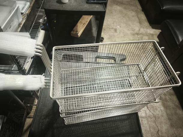 Brand new commercial wired mesh fry basket with front hook and black non-slip grip handle.
