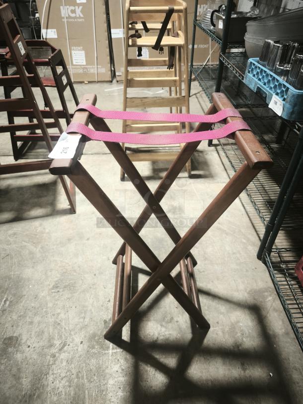 Folding wooden tray stand, 32-1/4" high, mahogany finish, pink straps, well-maintained, auction tag attached.