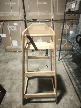Solid wood high chair with safety strap, natural finish; suitable for babies. Sturdy construction, good condition.