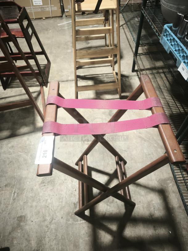 Folding wooden tray stand, 32-1/4" high, with vibrant pink straps. Tag reads "216, QTY 7." Sturdy construction, used condition.