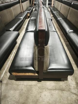 Double mid-channeled restaurant booth with headroll, black leather seats, wood frame, visible wear on the bottom edge.