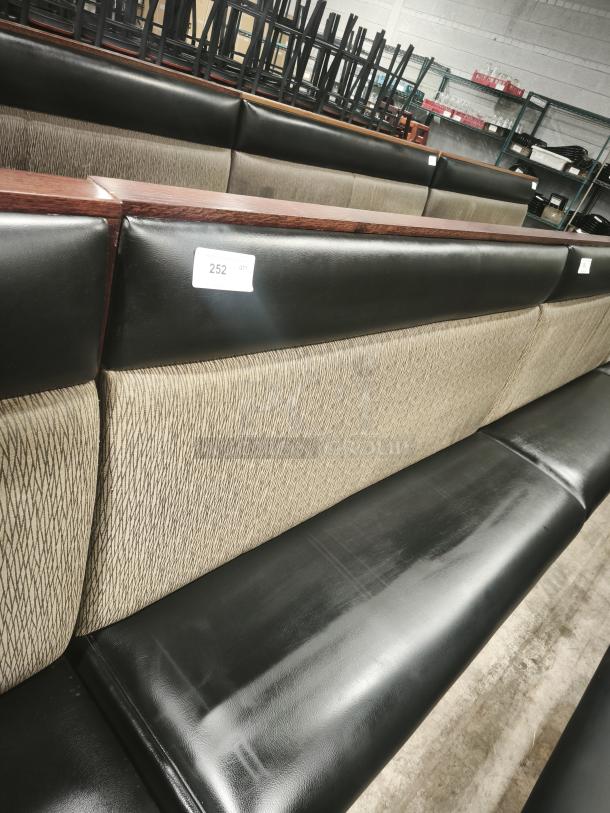 Double mid-channeled restaurant booth with headroll, black leather and beige fabric, excellent condition, tag labeled "252".