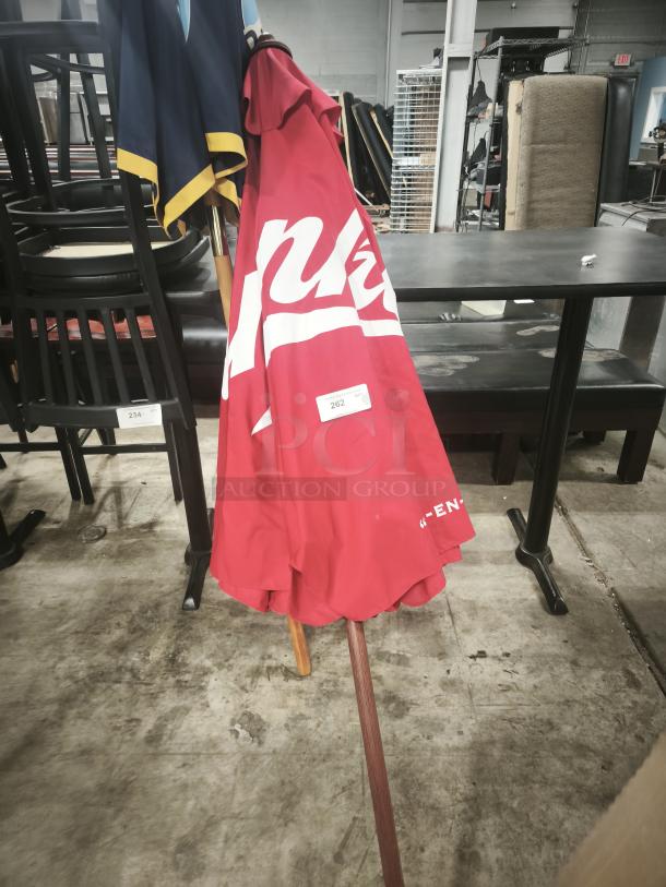 Red patio beer umbrella with logo, ideal for bar or restaurant use. Wooden pole, good condition, item tag 262 visible.