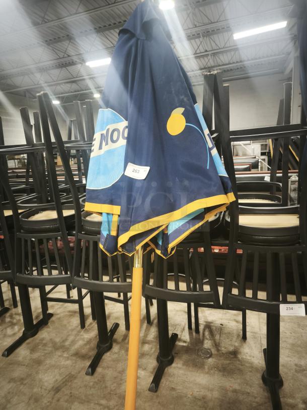 Folded Blue Moon branded patio beer umbrella with a wooden pole, suitable for bar or restaurant use. Slightly worn.
