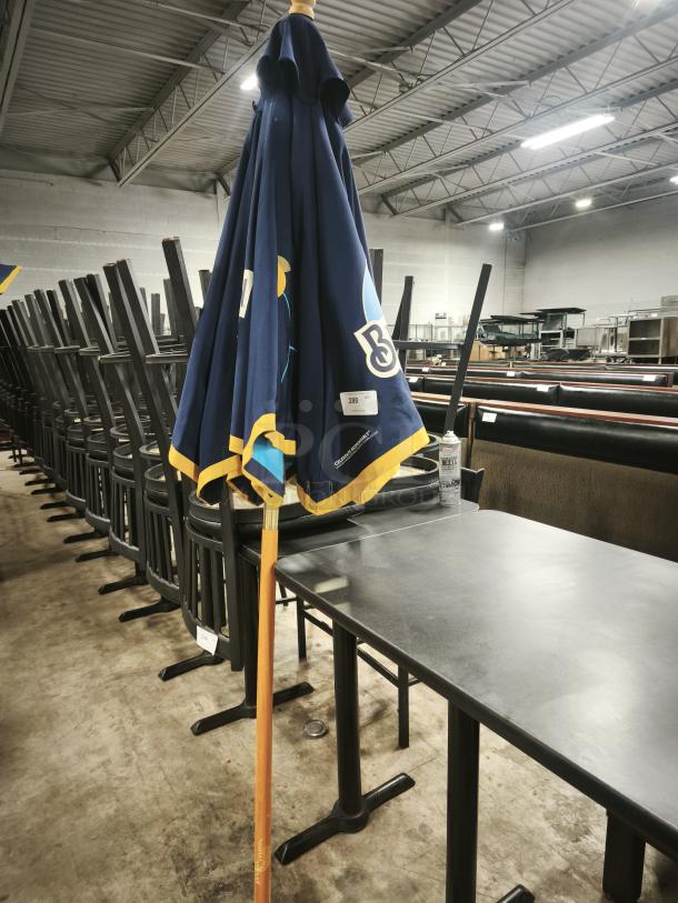 Blue patio beer umbrella for bar or restaurant, folded, wooden pole, branded logos visible, good condition.