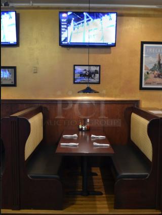 Rectangular table with fixed booth seating, dark wood finish, padded seats with patterned fabric, in a restaurant setting.