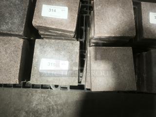 NSF Certified volcanic granite slabs for cooking food, shown stacked, each with adhesive labels indicating auction quantity and details.