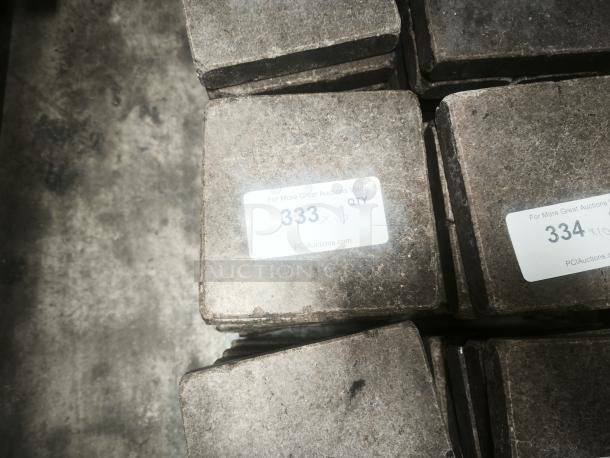 NSF certified volcanic granite slabs for cooking, stacked, with auction labels showing lot numbers 333 and 334.