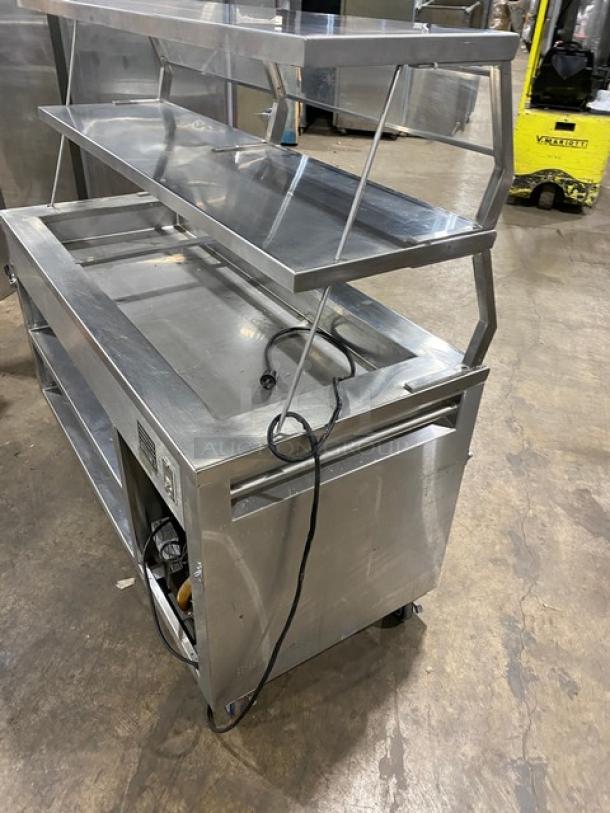 Precision SST2024RTNYC stainless steel refrigerated salad bar with double overhead sneeze guard, rear dry shelf base, on casters.
