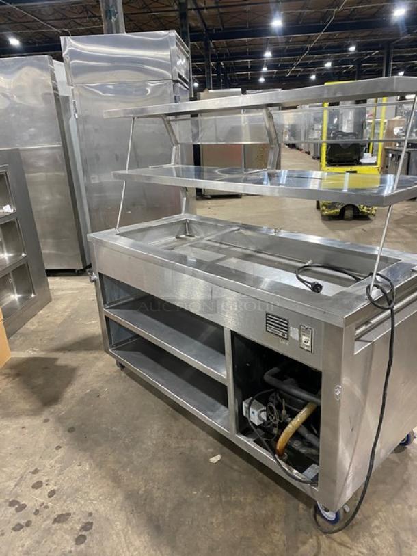 Precision stainless steel refrigerated salad bar, model SST2024RTNYC, with overhead shelf, sneeze guard, and caster wheels.