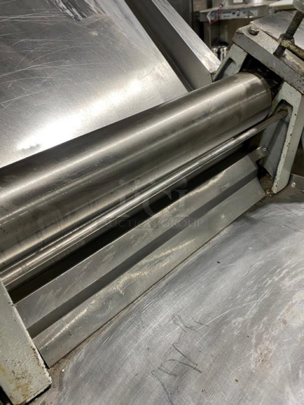 Commercial stainless steel electric dough roller/sheeter, high speed, on legs, minor surface wear, robust construction.