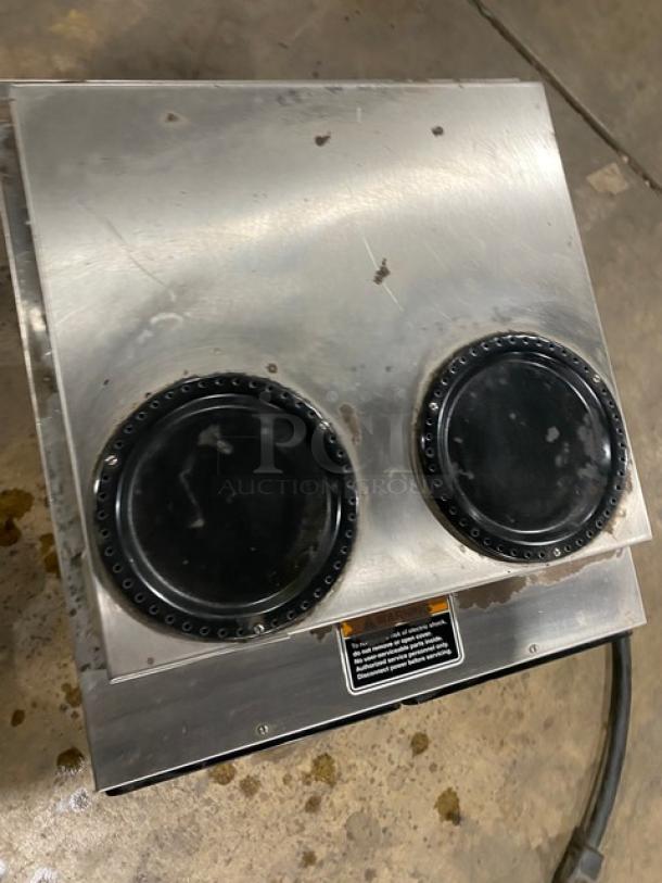 Bunn AXIOM22TWIN commercial coffee brewer, stainless steel, with 4 warming plates, visible wear, model and safety label shown.