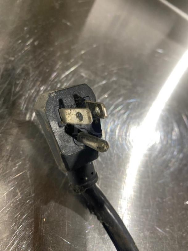 Photograph of a power plug for a Turbo Air M3 Series refrigerator on a stainless steel surface.