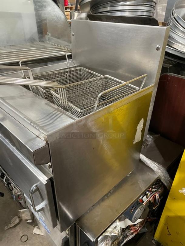 Commercial stainless steel gas countertop deep fat fryer with backsplash and fry basket, visible wear, sturdy build.