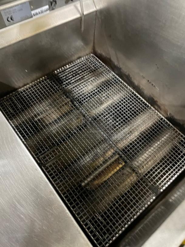 Commercial stainless steel gas-powered countertop deep fat fryer with backsplash and fry basket, in used condition.